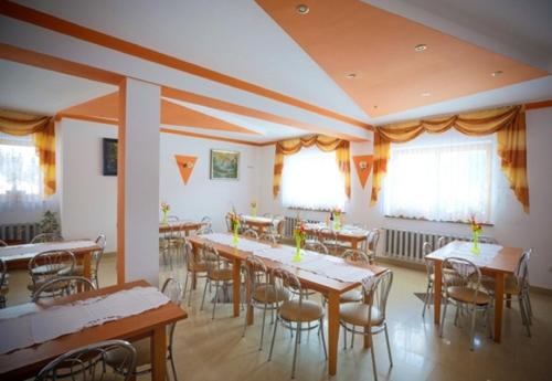 a dining room with tables and chairs and windows at Dziubasowka in Poronin