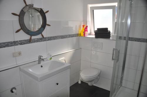 a bathroom with a sink and a toilet and a mirror at Hotel & Ferienunterkünfte Hus Seeblick in Fehmarn