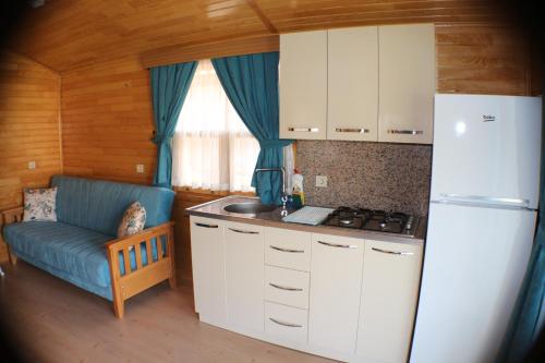 a kitchen with a refrigerator and a couch in a room at Villa Efsane Hotel in Cıralı