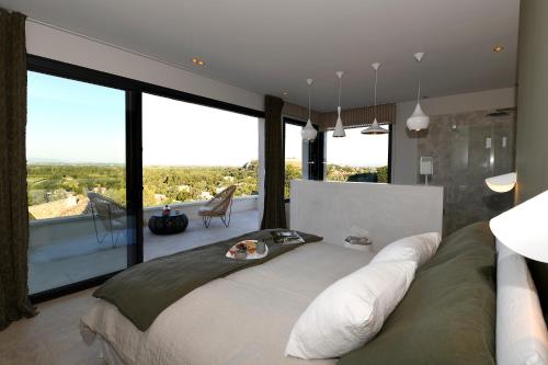 une chambre avec un grand lit avec une grande fenêtre dans l'établissement Les Loges En Provence 