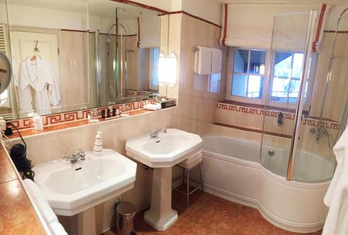 ein Badezimmer mit 2 Waschbecken, einer Dusche und einer Badewanne in der Unterkunft Residenz Heinz Winkler in Aschau im Chiemgau