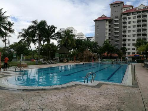 a large swimming pool with chairs and buildings at Glory 3 Room Seaview Getaway in Port Dickson