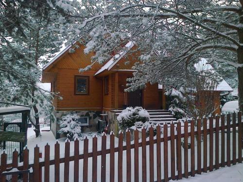 une maison en bois avec une clôture dans la neige dans l'établissement Dom LECH Kaszuby do 8 os., à Olpuch