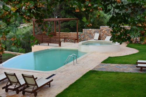 a pool in a yard with chairs and a bench at Ellinospito in Axós