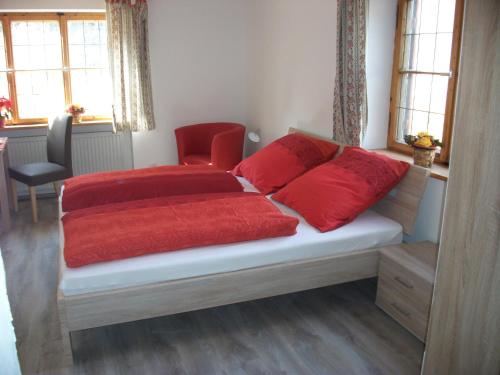 a bedroom with a bed with red pillows on it at Haus Alpenrose in Schwangau