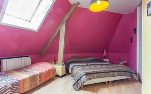 two beds in a room with pink walls at Les Champs De La Mer in Auberville-la-Renault
