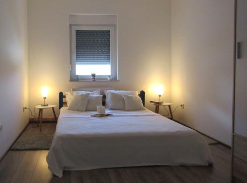 a bedroom with a large white bed with two lamps at Apartment & Room Renee in Osijek