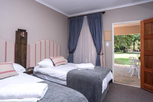 a bedroom with two beds and a sliding glass door at Welverdiend Guesthouse and Venue in Piet Retief