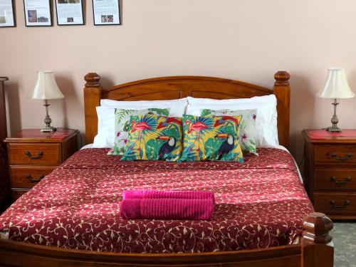 a neatly made bed with a white comforter and pillows at Albany Foreshore Guest House in Albany