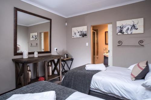 a bedroom with two beds and a mirror at Welverdiend Guesthouse and Venue in Piet Retief