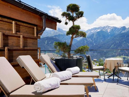 a group of chairs and tables on a balcony with mountains at Hotel Tirol Fiss 4Sterne Superior in Fiss