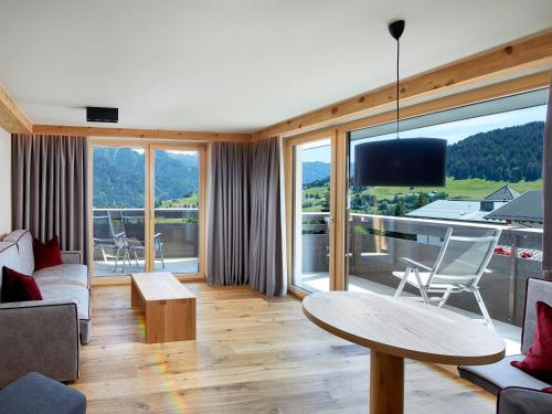 a living room with a table and a large window at Hotel Tirol Fiss 4Sterne Superior in Fiss