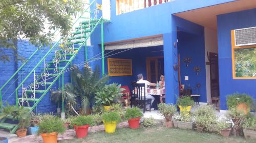 a person sitting at a table outside of a blue house at The Coral Tree Boutique Homestay in Agra