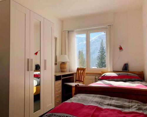 Schlafzimmer mit einem Bett und einem Fenster in der Unterkunft La Cabana 5 Arosa in Arosa