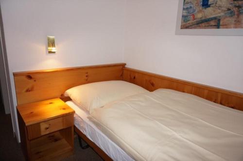 アローザにあるParadies 205のベッド(木製のヘッドボード、ナイトスタンド付)
