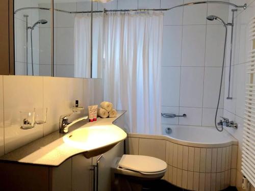 ein Badezimmer mit einem Waschbecken, einem WC und einer Badewanne in der Unterkunft La Cabana 5 Arosa in Arosa