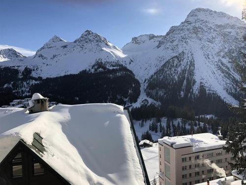a snow covered roof of a building with mountains in the background at La Cabana 5 Arosa in Arosa