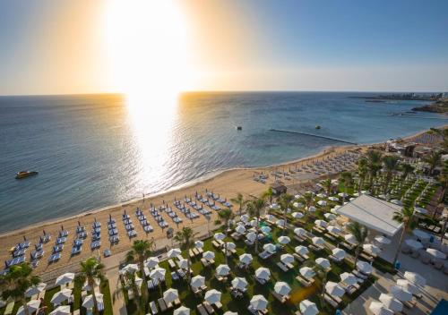 eine Luftansicht auf einen Strand mit Sonnenschirmen und dem Meer in der Unterkunft Constantinos the Great Beach Hotel in Protaras