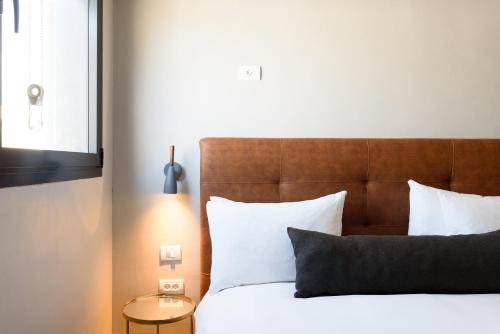 a bed with a wooden headboard and white pillows at The Roof - By Sea Land Suites in Tel Aviv