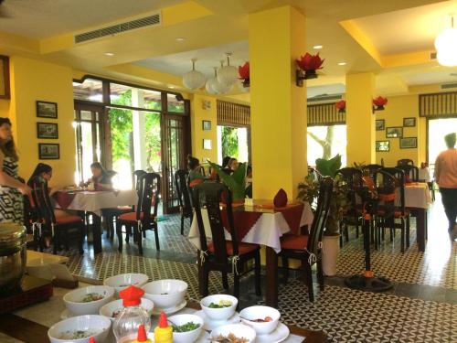 a restaurant with tables and people sitting at tables at Vinh Hung Old Town Hotel in Hoi An