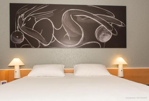 a bedroom with a bed with two white pillows at ibis La Bresse Gérardmer in La Bresse