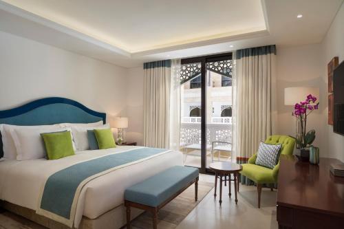 Al Najada Doha Hotel Apartments by Oaks في الدوحة: غرفة نوم بسرير وطاولة وكراسي