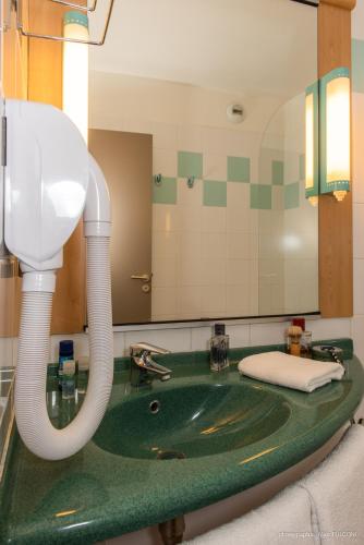a bathroom with a green sink and a mirror at ibis La Bresse Gérardmer in La Bresse