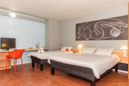 a hotel room with two beds and a tv at ibis La Bresse Gérardmer in La Bresse