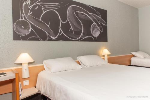 a bedroom with two beds and a painting on the wall at ibis La Bresse Gérardmer in La Bresse