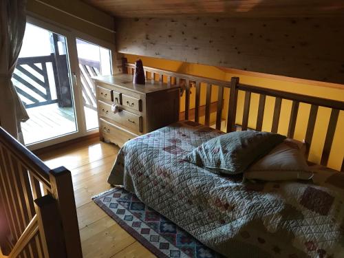 a bedroom with a bed and a dresser and a window at Les Loges du Lac - Appartement avec Terrasse in Gérardmer