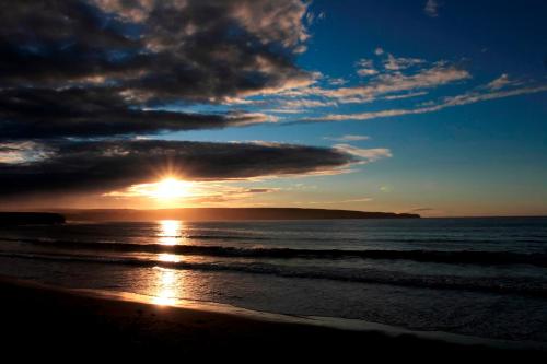 a sunset on the beach with the sun setting at Castletown Hotel in Castletown