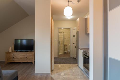a living room with a television and a kitchen at Apartamenty Koba in Ustroń