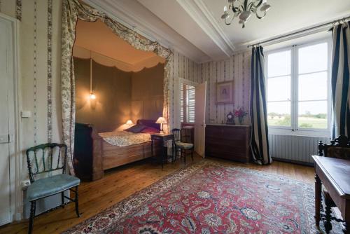 a bedroom with a bed and a chair and a rug at Le Rossay in Saint-Clément-de-la-Place