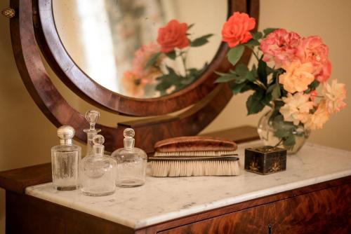 a table with two bottles and a mirror and flowers at Le Rossay in Saint-Clément-de-la-Place