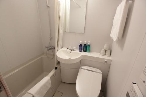 a white bathroom with a toilet and a sink at Takamatsu Century Hotel in Takamatsu