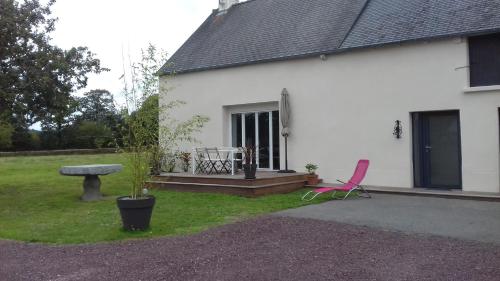 a pink chair sitting outside of a white house at le bois du loup en brocéliande in Paimpont