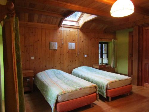 2 camas en una habitación con paredes de madera y ventana en La Boissellerie, en Saulxures-sur-Moselotte