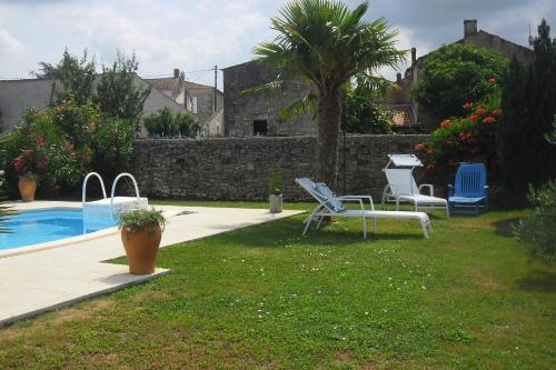 une cour avec une piscine, des chaises et un palmier dans l'établissement La Luzacaise, à Saint-Just