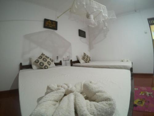 a white bedroom with two beds with blankets at Palitha Homestay in Sigiriya