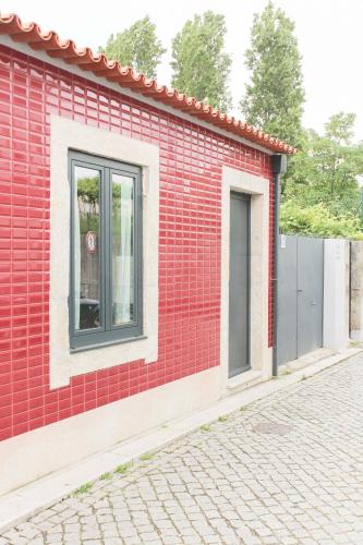 a red brick building with two windows on a street at Garden House Ramalde in Porto