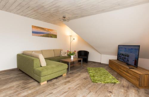 a living room with a couch and a tv at Ferienwohnung Haus zum Seehund mit Pool und Frühstücksoption in Bensersiel