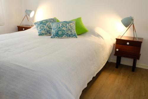 a white bed with two pillows and a night stand at Vale Coelhos Casa de Campo in Sarnadela