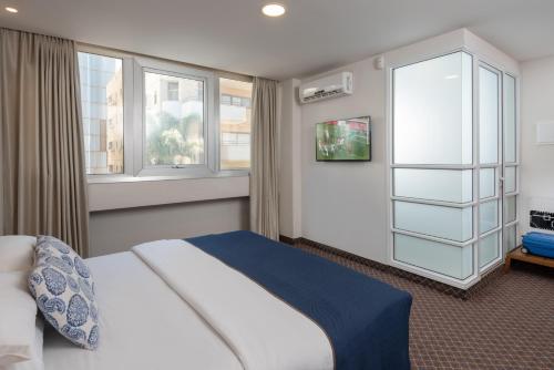 a bedroom with a bed and two windows at Embassy Hotel Tel Aviv in Tel Aviv