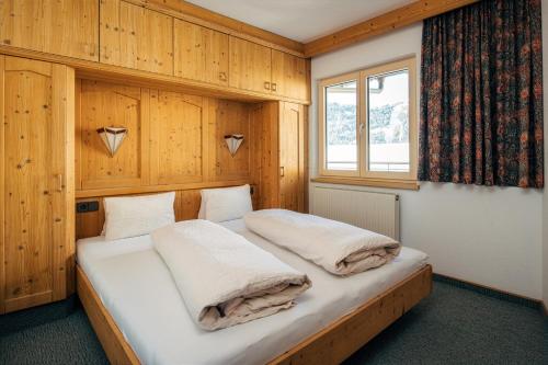 a bedroom with a bed with wooden walls and a window at Appartement Fossa in Fiss