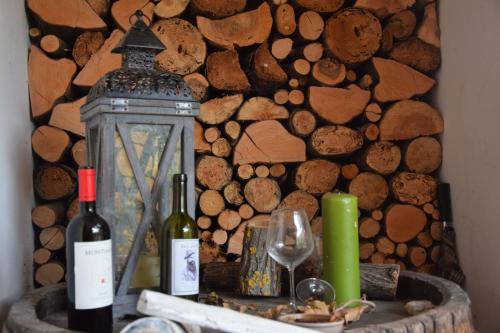 two bottles of wine and a lantern next to a wall of logs at Bio Agriturismo Valle dei Calanchi in Castiglione in Teverina