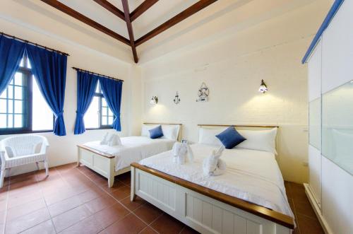 2 Betten in einem Zimmer mit blauen Vorhängen in der Unterkunft Hasayaki Homestay in Dayi