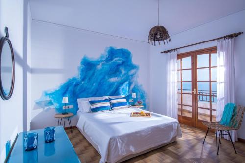 - une chambre avec un grand lit orné d'une peinture bleue sur le mur dans l'établissement Helidoni Hill seaview family villa, à Palaiokastro