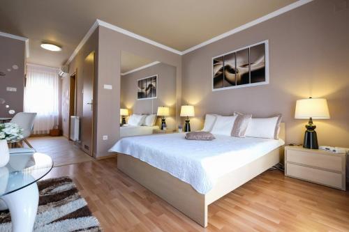 1 dormitorio con 1 cama blanca grande y 2 lámparas en Novák Apartman, en Gyula