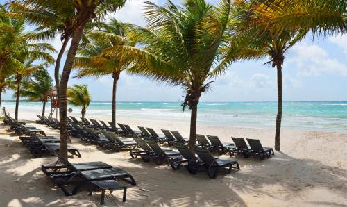a row of chairs on a beach with palm trees at Catalonia Royal Tulum Beach & Spa Resort Adults Only - All Inclusive in Xpu Ha