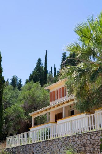 a house on a hill with a palm tree at Odyssey Hotel in Agios Nikitas